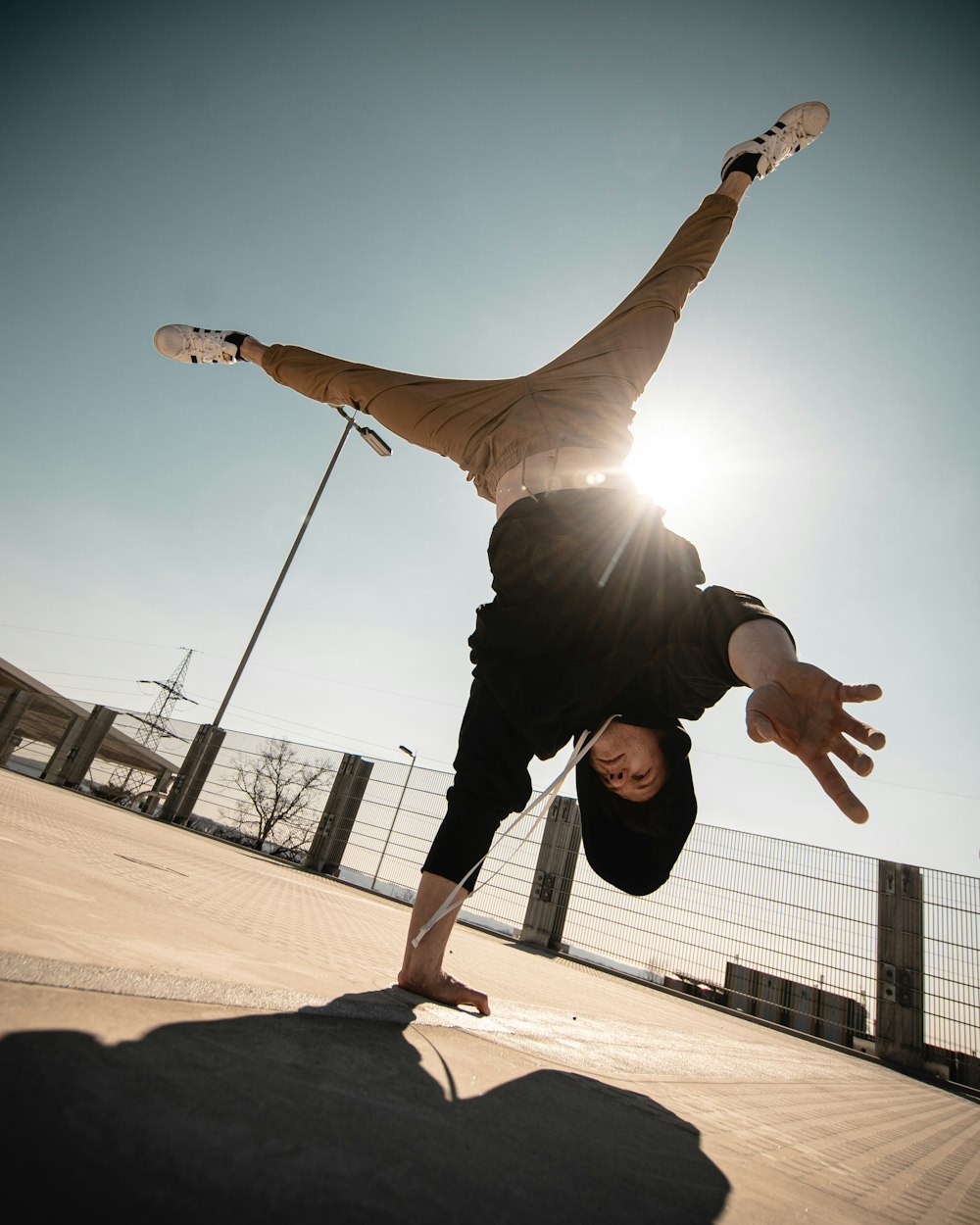 man in black jacket and black pants jumping on brown sand during daytime