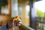 Hands grabbing a slice of pizza, showing the stretch of gooey cheese in a lively restaurant scene.