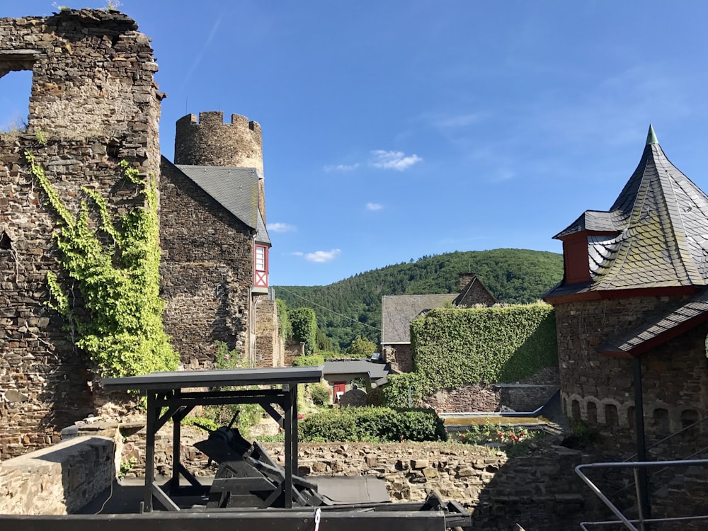 brown brick building near green trees and mountain under blue sky during daytime