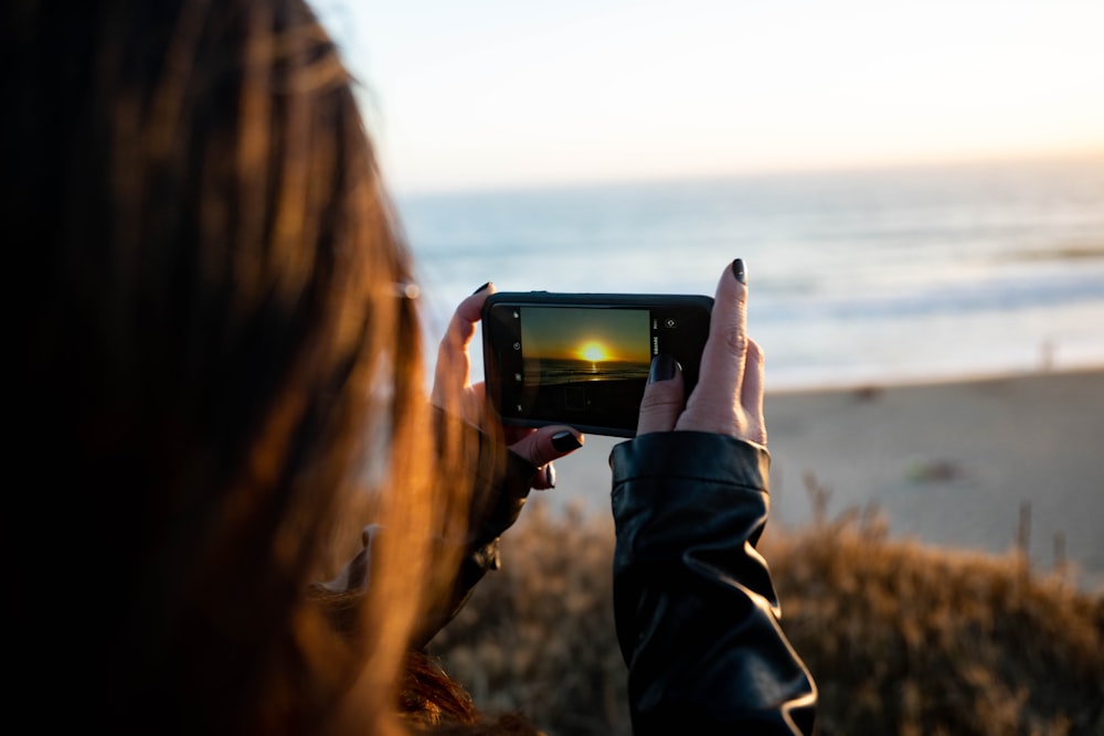 woman taking photo of sea during daytime