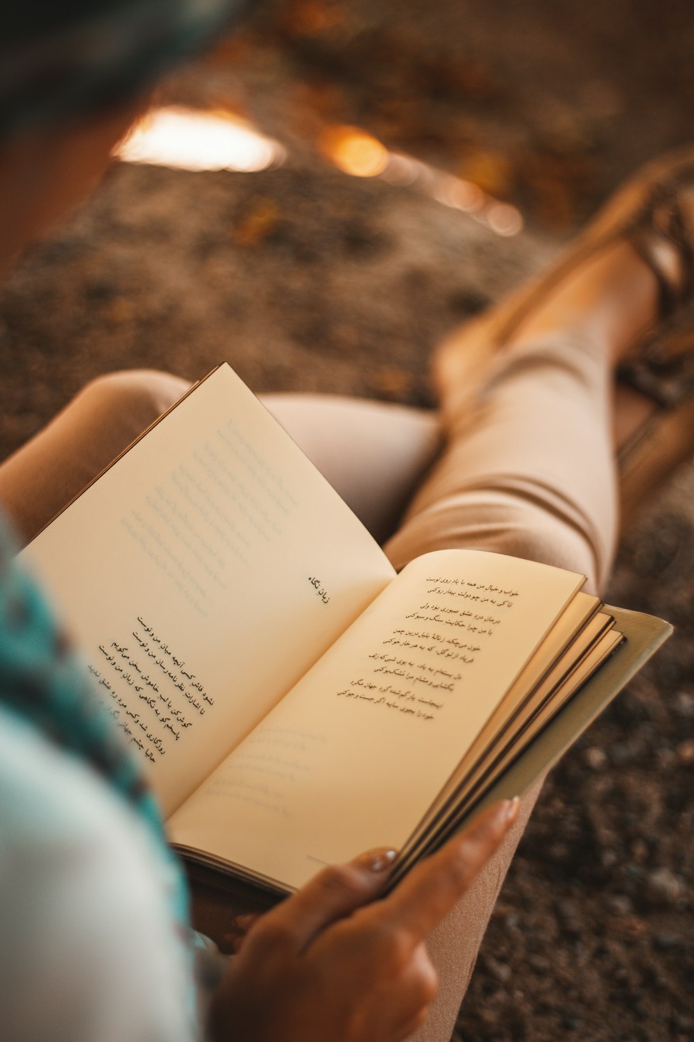 person reading book on brown and black marble table