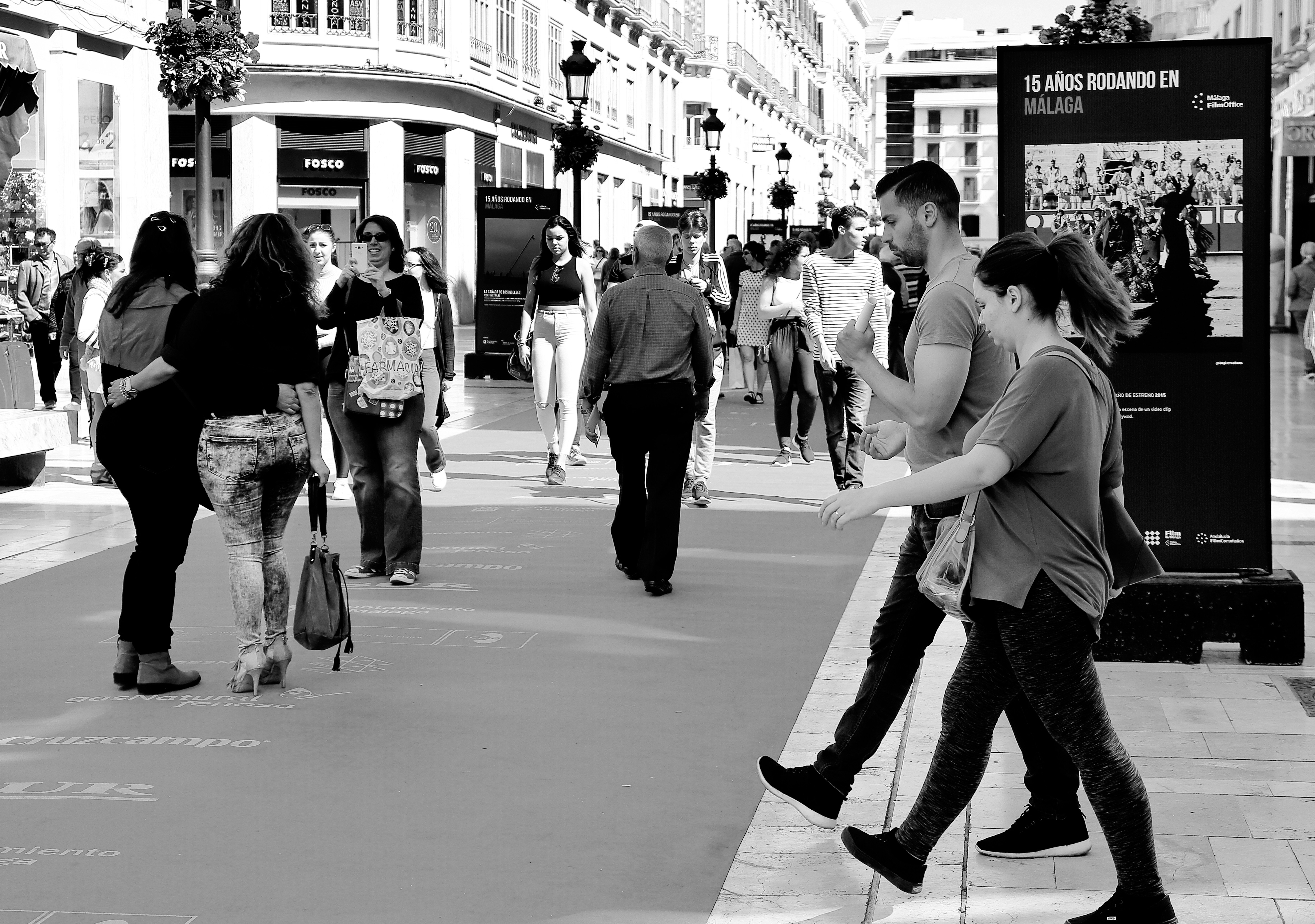 grayscale photo of woman in tank top and pants walking on street