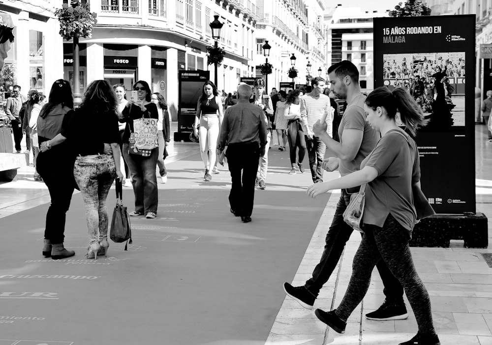 grayscale photo of woman in tank top and pants walking on street