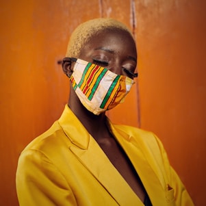 man in yellow suit jacket with white and black mask