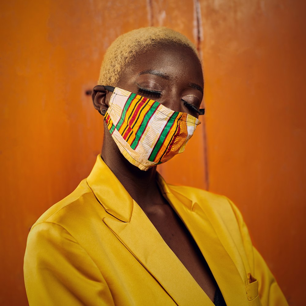 man in yellow suit jacket with white and black mask