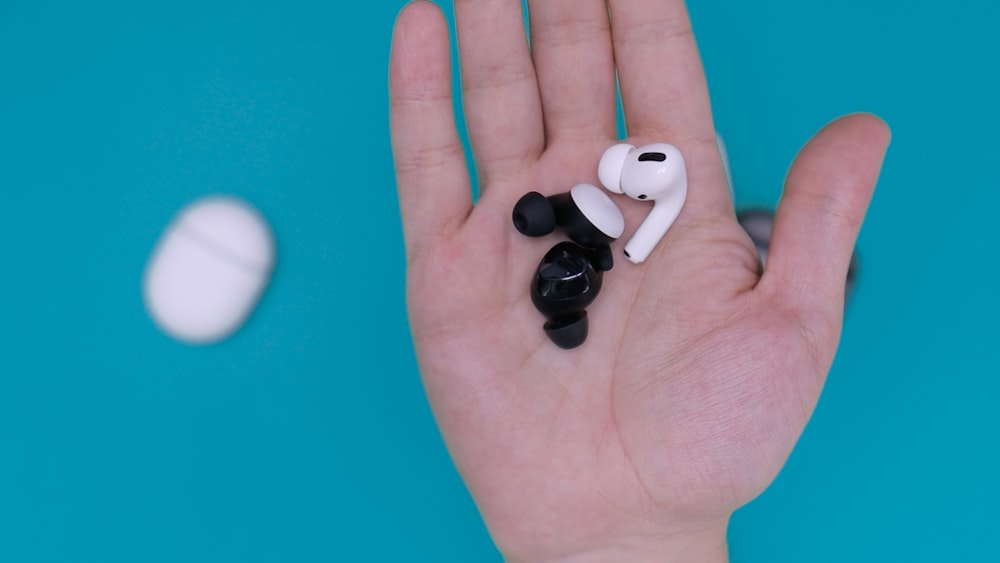 Auriculares blancos y negros en la mano de las personas