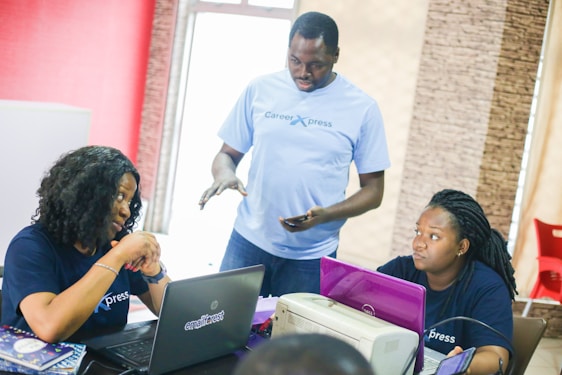 A friendly IT specialist assisting a small business team with Microsoft 365 on their laptops.