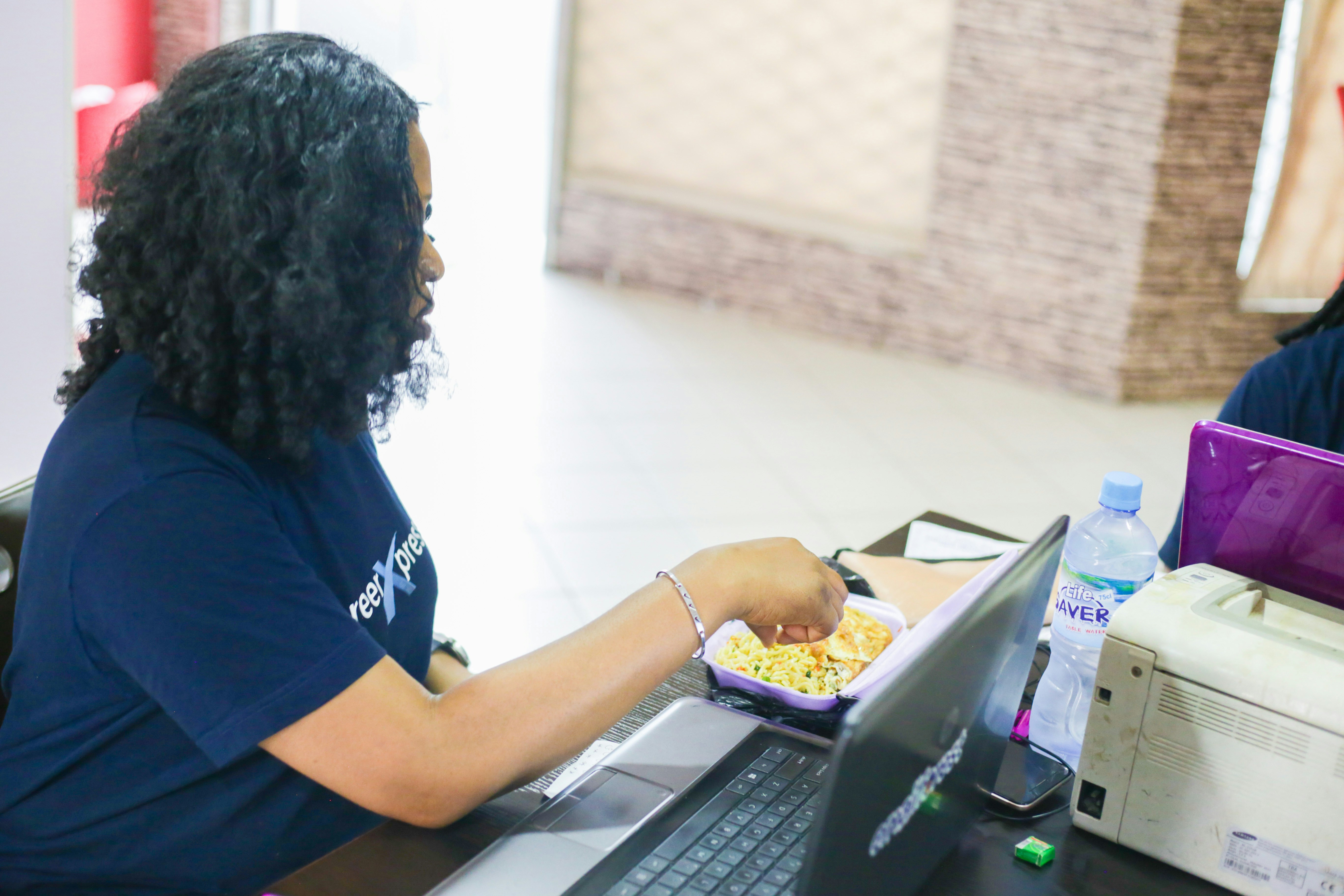 A skilled nail technician carefully applying an acrylic bead to a client's nail in a well-lit Lagos salon.