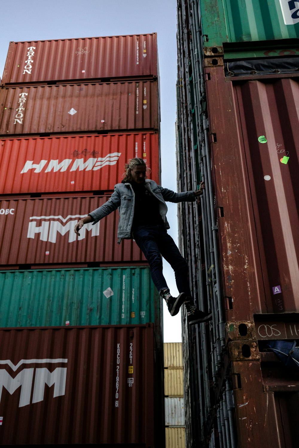 man in black leather jacket and black pants jumping on red and green wall during daytime