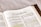 An open book displaying a page from the Bible, specifically from the book of 2 Corinthians. The text includes paragraphs and highlighted passages with yellow marker. The focus is primarily on the printed and highlighted text.