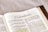An open book displaying a page from the Bible, specifically from the book of 2 Corinthians. The text includes paragraphs and highlighted passages with yellow marker. The focus is primarily on the printed and highlighted text.
