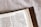 An open book featuring a page from the Bible with text from 1 Corinthians 7:9. The book has a brown leather cover and is resting on a light-colored surface.