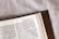 An open book featuring a page from the Bible with text from 1 Corinthians 7:9. The book has a brown leather cover and is resting on a light-colored surface.