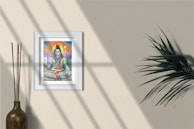 A framed artwork featuring a colorful depiction of a deity is mounted on a beige wall. Natural light casts soft shadows across the surface. To the left, a narrow vase contains a bundle of tall, thin sticks. To the right, a green leafy plant adds a touch of nature to the scene.