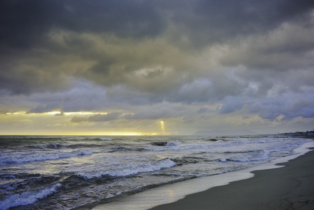 ocean waves crashing on shore during sunset