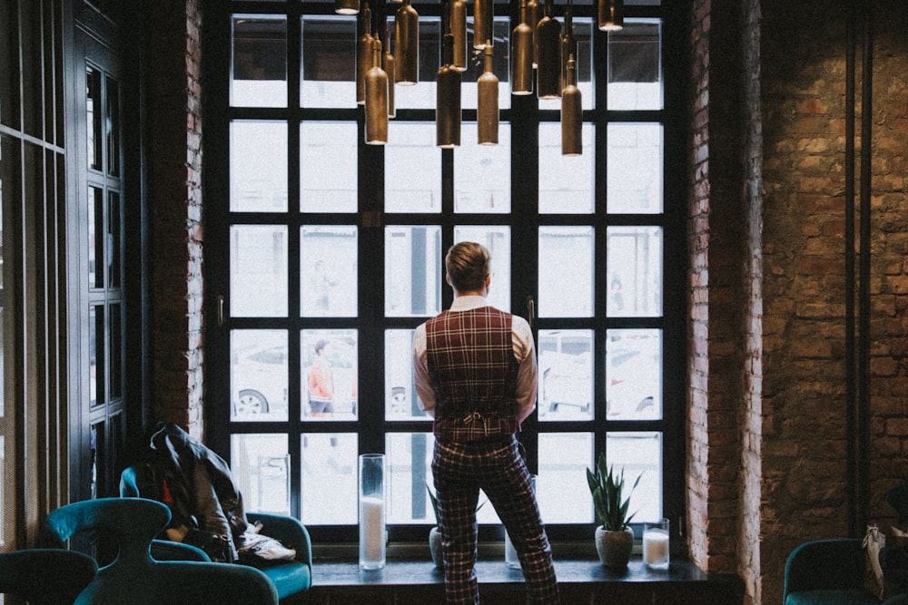 man in blue and white plaid dress shirt standing near window