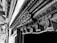 Ornate and intricate wooden carvings adorn a structure, displaying detailed patterns and craftsmanship. The carvings include floral and geometric motifs along a wooden beam or doorway, highlighting the skill and artistry involved.