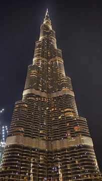 A towering commercial skyscraper reflecting the city skyline at dusk, with glowing windows and strong steel framework.