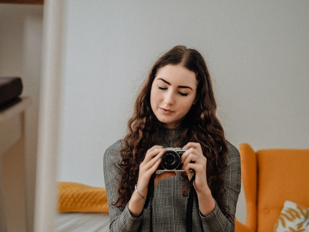 woman in gray knit sweater holding camera
