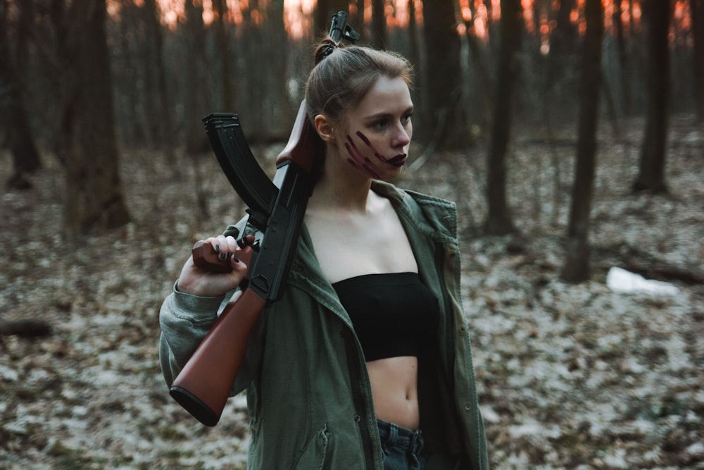 woman in black leather jacket holding black rifle