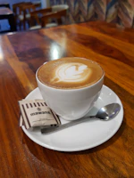 A steaming cup of coffee beside a plate of crispy momos on a wooden table.