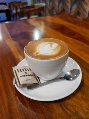 A steaming cup of coffee beside a plate of crispy momos on a wooden table.