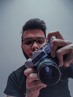 A close-up of a filmmaker adjusting a vintage camera lens, focused and intent.