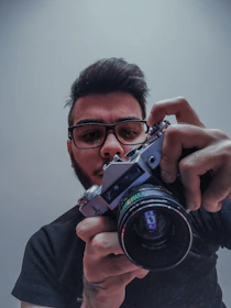 Close-up of a vintage film camera lens capturing a director's focused expression.