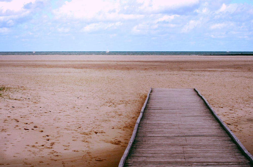 brown wooden dock on brown sand under blue sky during daytime