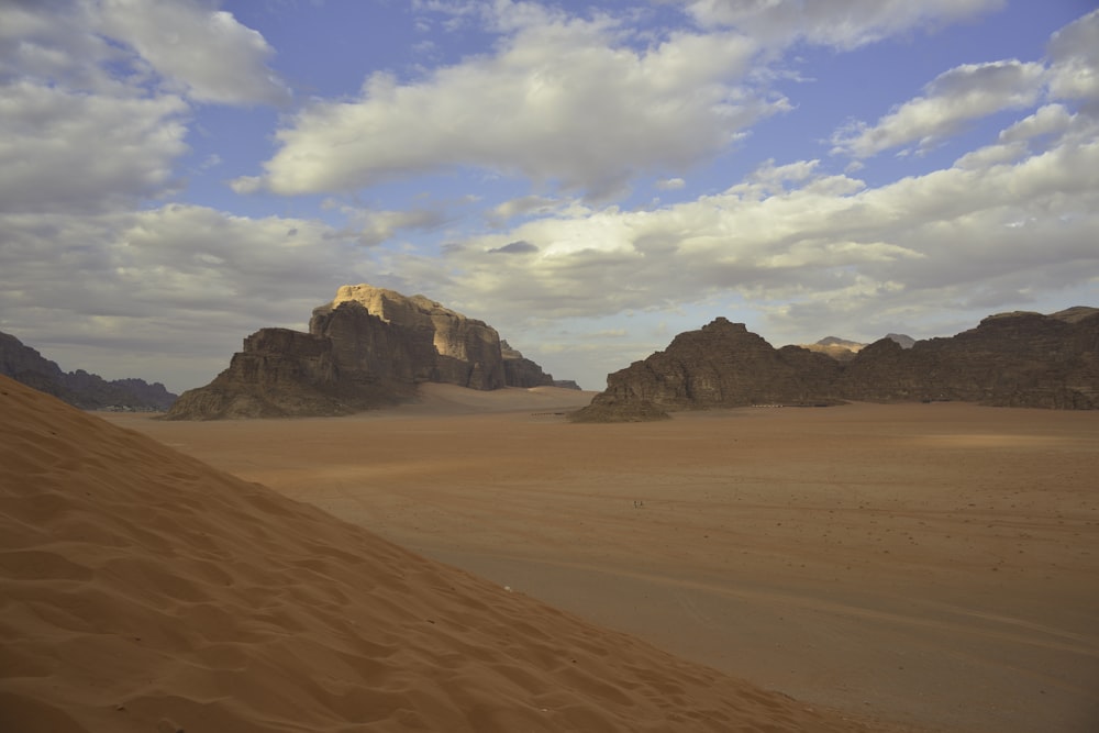 brown sand under white clouds and blue sky during daytime