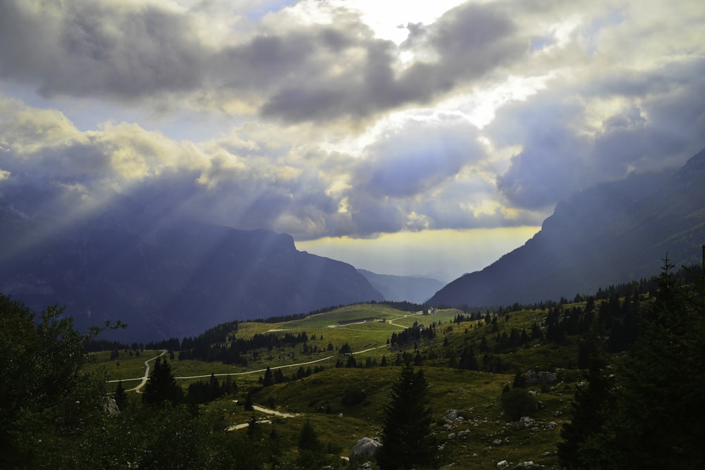 昼間の白い雲の下の山の緑の木々