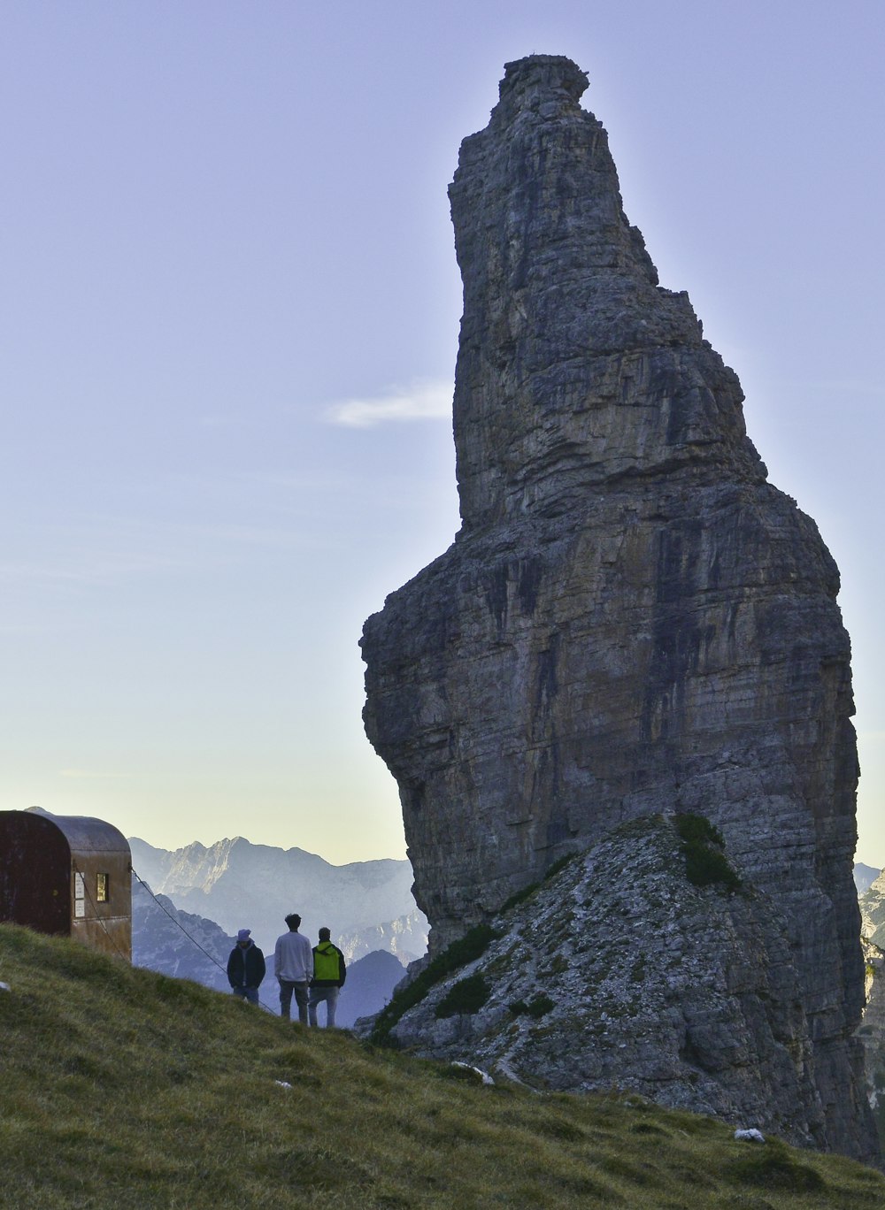 people walking on green grass field near brown rock formation during daytime