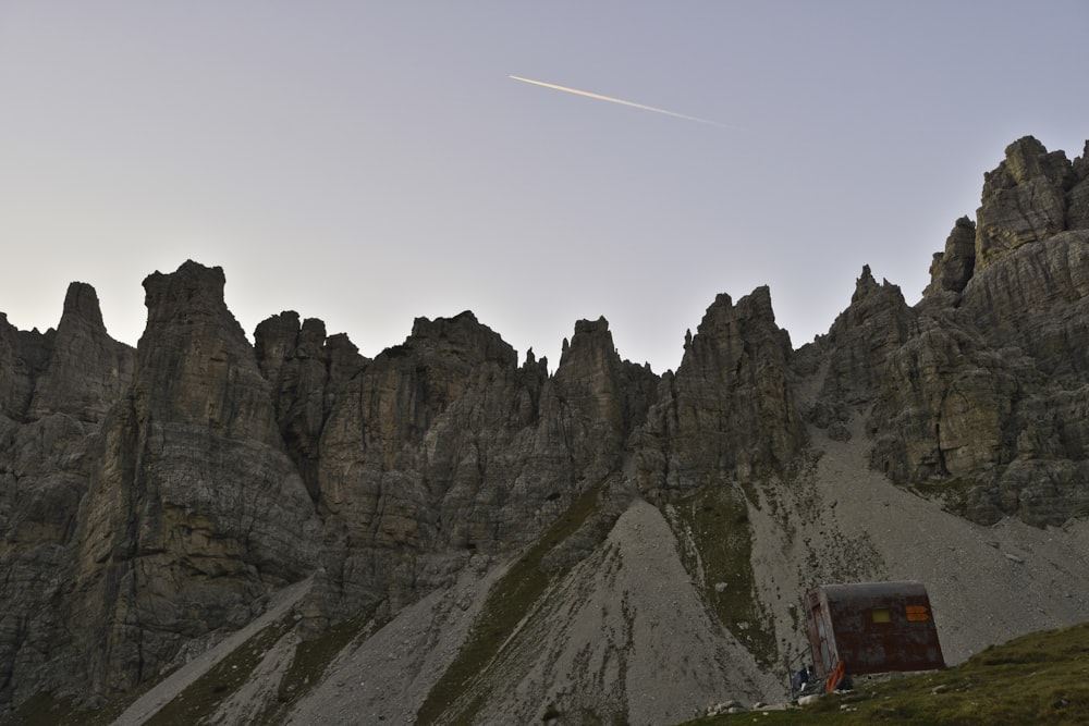 Autobus rosso e nero sulla strada vicino alla montagna rocciosa marrone sotto il cielo blu durante il giorno