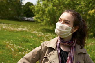 A smiling person wearing a pastel-colored aerisana mask while walking through a sunny park.