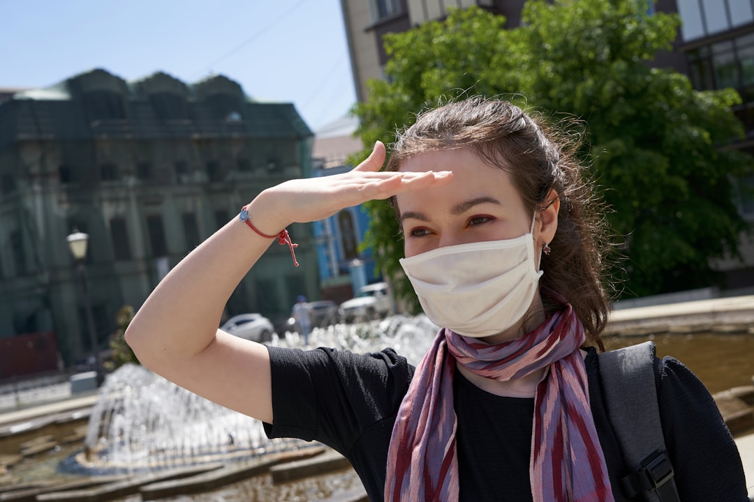 woman in black long sleeve shirt covering her face with white mask