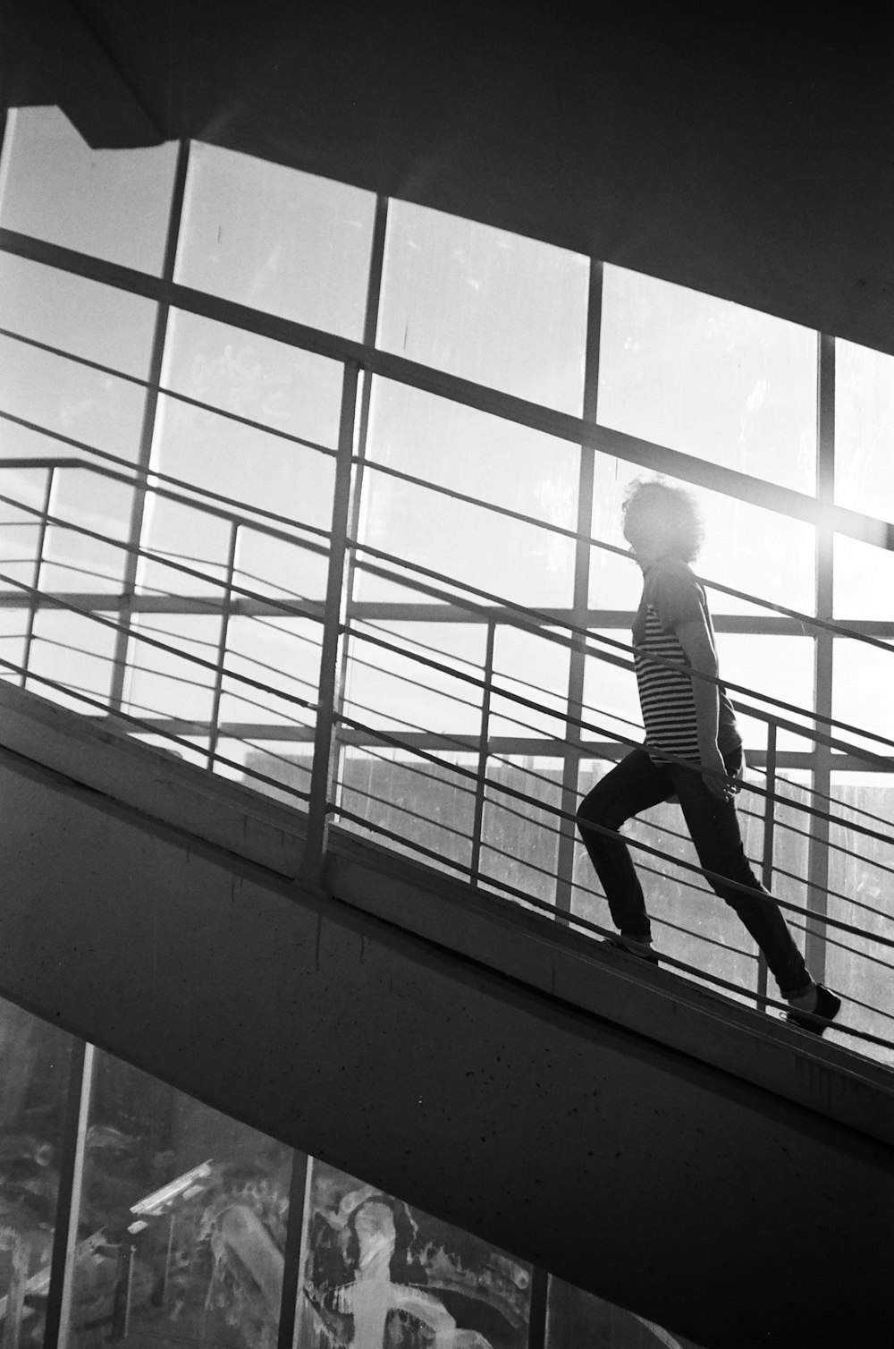 grayscale photo of man in white shirt and black pants standing on window