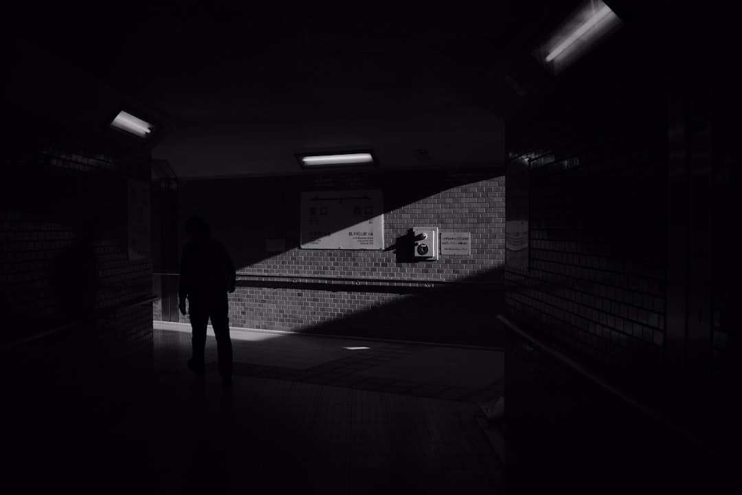 grayscale photo of man and woman walking on hallway