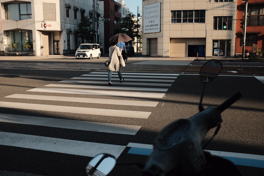 woman in white shirt and black pants walking on pedestrian lane during daytime