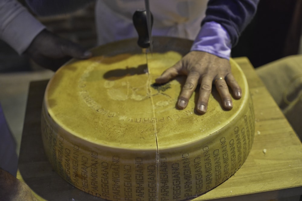 person holding brown wooden round container