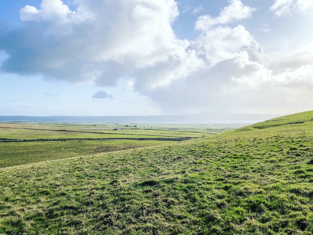 green grass field under white clouds during daytime