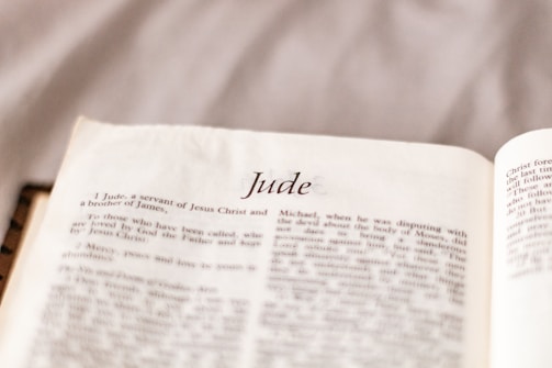 An open book displaying text with the heading 'Jude' prominently centered on the page. The page is filled with paragraphs of printed text in a serif font on an off-white background.