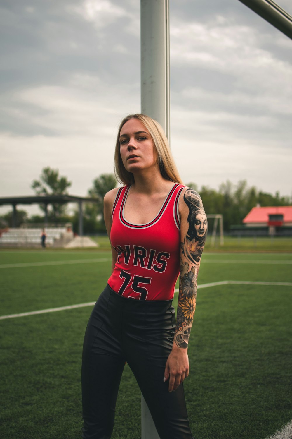 Woman in red tank top and black leggings standing on green grass