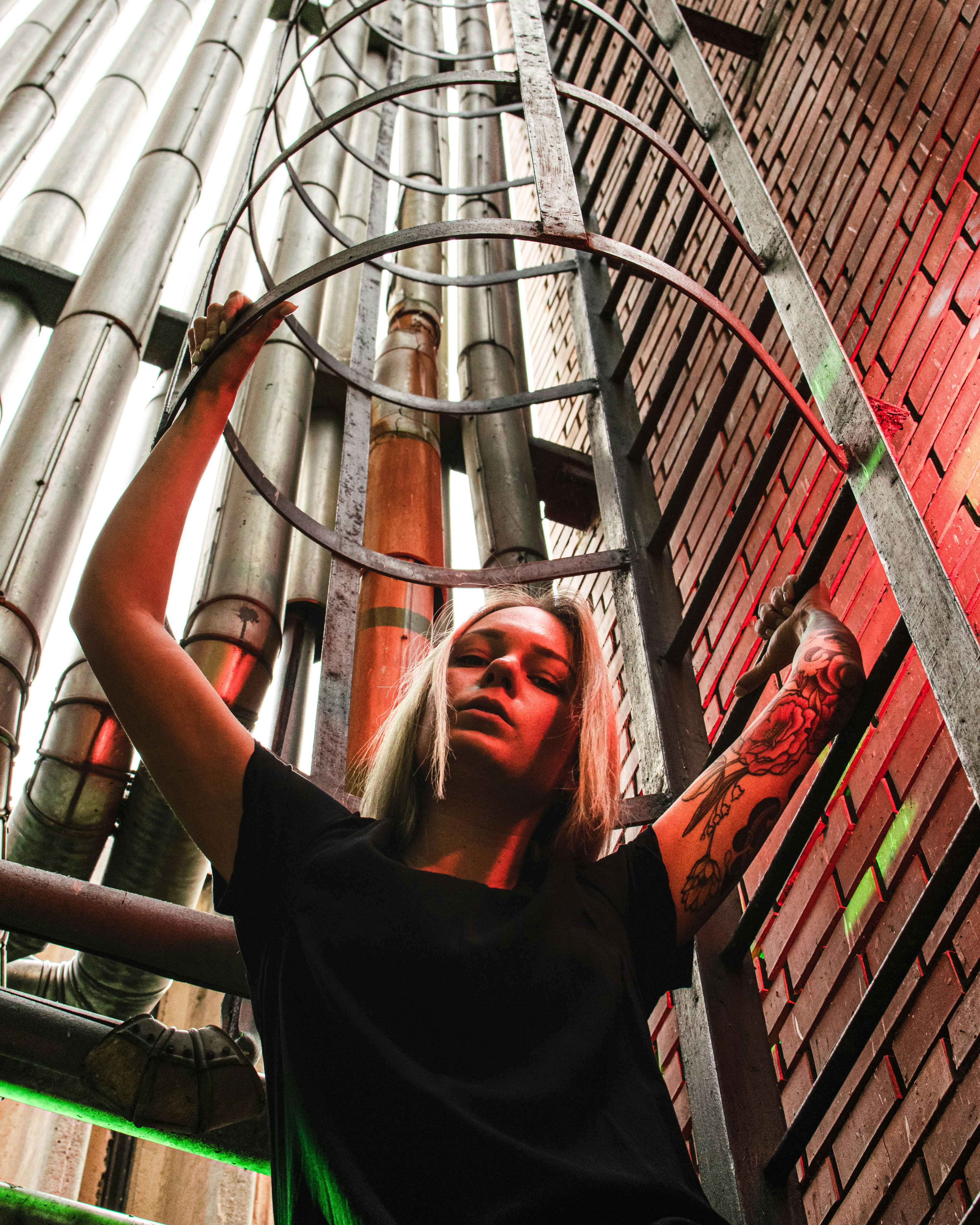 woman in black t-shirt standing on brown metal pipe