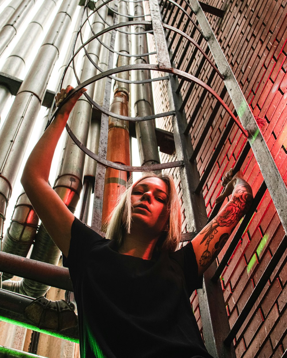 woman in black t-shirt standing on brown metal pipe