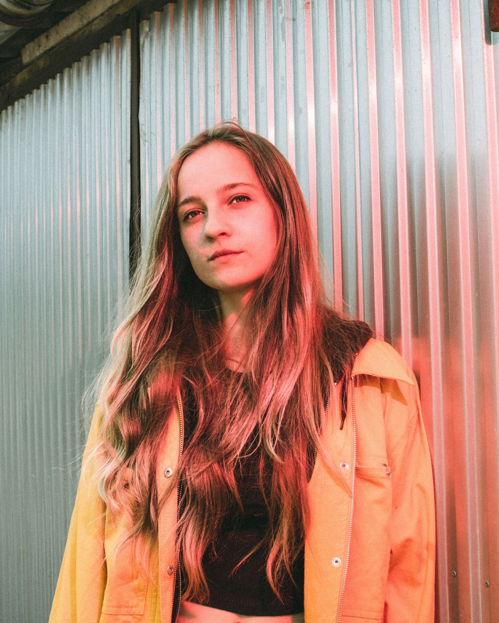 woman in brown coat standing near gray wall