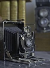 Vintage stereoscopic camera and viewer displayed on a wooden table with old 3D cards.