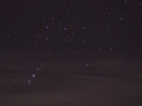 Dark starry night sky with mysterious glowing purple nebula.