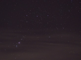 A glowing purple star shining over a night sky filled with constellations.