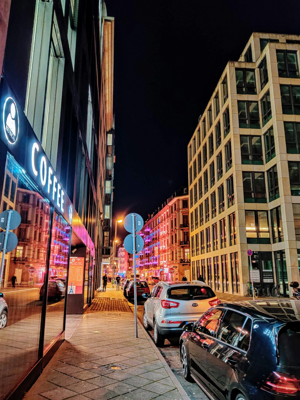 cars parked on side of the road in front of building during night time