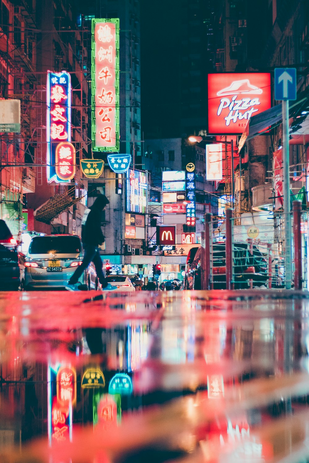 man in black jacket and black pants walking on street during night time